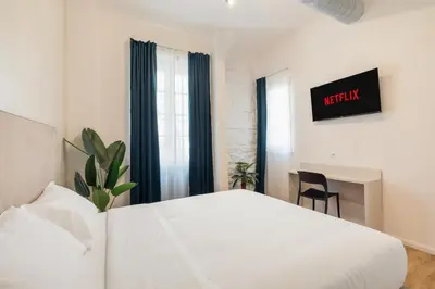 a hotel room with a white bed and a chair at Adelante Apartment in Rome