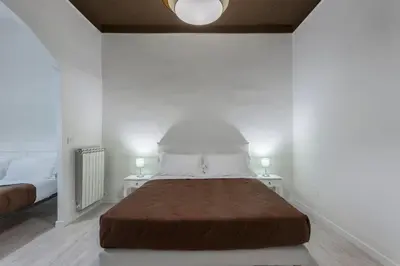 a bed in a white room with two white tables at Gilda Apartment New elegant apartment in Termini in Rome