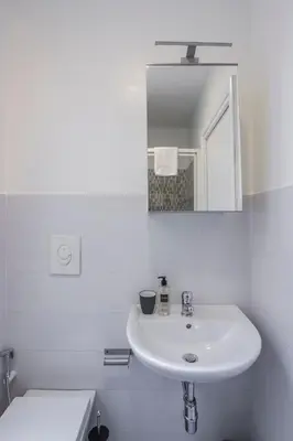 a white bathroom with a sink and a mirror at Gilda Apartment New elegant apartment in Termini in Rome