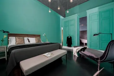a bedroom with blue walls and a bed and a chair at Daniele Manin Roma in Rome