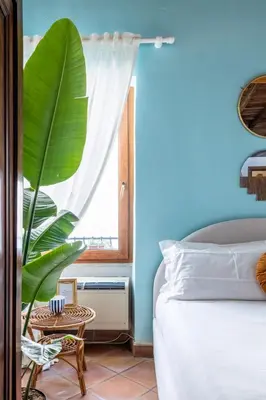 a bedroom with a bed and a large green plant at Suite Trevi - Charming Loft Near Trevi Fountain in Rome