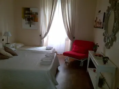 a bedroom with two beds and a red chair at Holiday Home House Fornaci in Rome