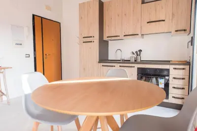 a kitchen with a wooden table and white chairs at San Peter's - Cosy Renovated Penthouse in Rome
