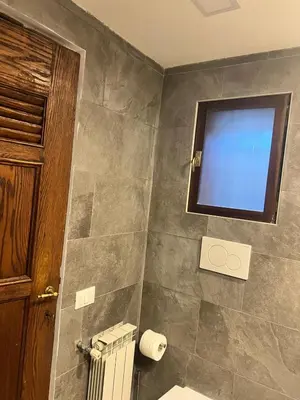 a bathroom with a television on a tiled wall at Imperial House San Calisto 7 in Rome
