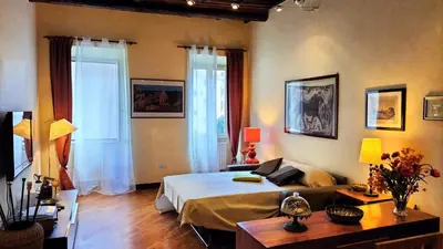 a bedroom with a bed and a table and two windows at Benedetta Suite Trastevere in Rome