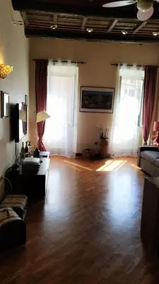 a living room with a wooden floor and two windows at Benedetta Suite Trastevere in Rome