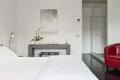 a bedroom with a white bed and a red chair at Xenia Guest House in Rome