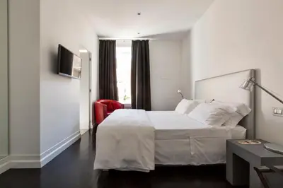 a bedroom with a white bed and a red chair at Xenia Guest House in Rome