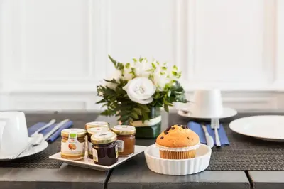 a table with a cupcake and jam and a vase of flowers at Xenia Guest House in Rome