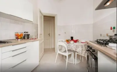 a white kitchen with a table with a table cloth at Re di Roma House in Rome