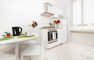a white kitchen with a table and a stove at Re di Roma House in Rome