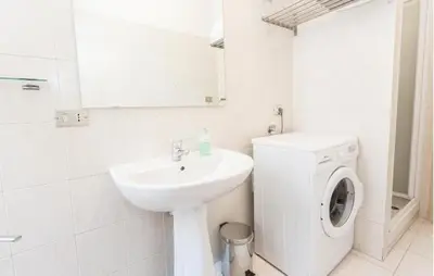 a white bathroom with a washing machine and a sink at Re di Roma House in Rome