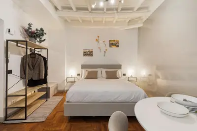 a white bedroom with a bed and two tables at Fiori Suite in Rome