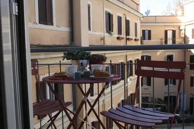a table on a balcony with two chairs at Houses Donatello & Tiziano Roma in Rome