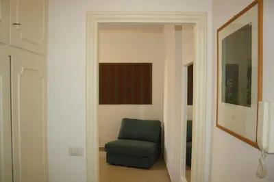 a blue chair in a hallway with a painting at Houses Donatello & Tiziano Roma in Rome