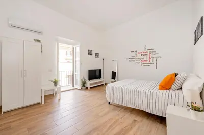 a white bedroom with a bed and a tv at central comfortable studio apartment in Rome