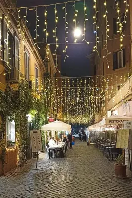 a street with people sitting at tables under lights at Porta Labicana House -10 minutes from Termini Station in Rome