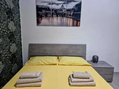 a bedroom with a yellow bed with two towels on it at Tiburtina Keys - Roma in Rome