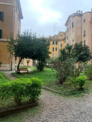 a park with a bench and trees and buildings at Colosseo Home San Giovanni in Rome