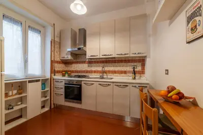 a kitchen with white cabinets and a table with a bowl of fruit at San Paolo Apartment - Charme Holidays in Rome