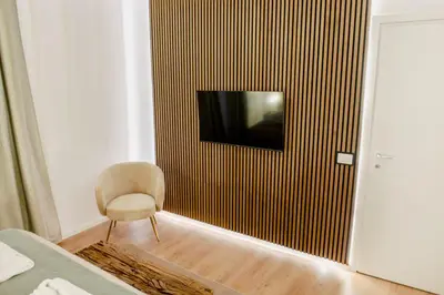 a bedroom with a chair and a television on a wall at Minerva Boutique Residence in Rome