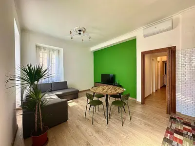 a living room with a green wall and a table and chairs at MuMo Home Pigneto in Rome