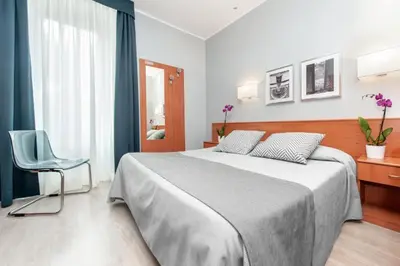 a bedroom with a large bed and a chair at Reyes Suite & Rooms in Rome