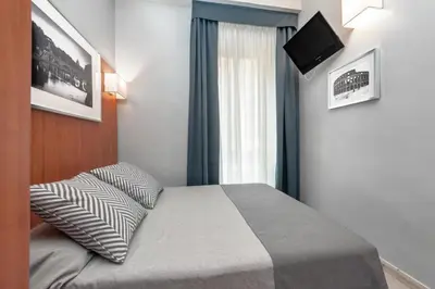 a bedroom with a bed with a television on the wall at Reyes Suite & Rooms in Rome