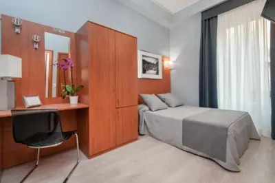 a bedroom with a bed and a desk with a computer at Reyes Suite & Rooms in Rome