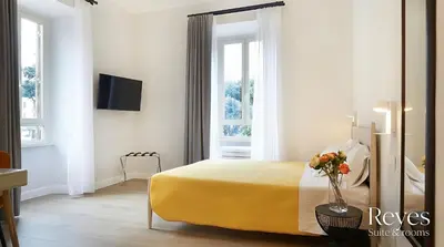 a bedroom with a yellow bed with a vase of flowers at Reyes Suite & Rooms in Rome