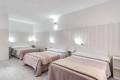 a room with three beds with pink sheets at AltaDomus Roma in Rome