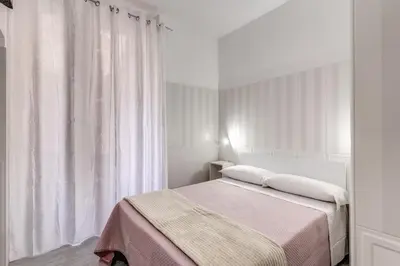 a white bedroom with a bed and a window at AltaDomus Roma in Rome