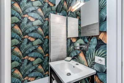 a bathroom with a sink and a leafy wallpaper at AltaDomus Roma in Rome