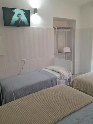 a room with two beds and a tv on the wall at AltaDomus Roma in Rome