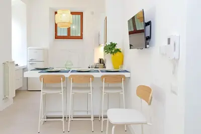 a white kitchen with a counter and stools at Vatican apartment with parking in Rome