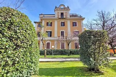 a large yellow building with a clock tower behind two bushes at Vatican apartment with parking in Rome