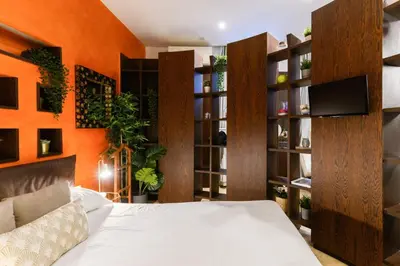 a bedroom with an orange wall with a bed and shelves at Trastevere Charme in Rome