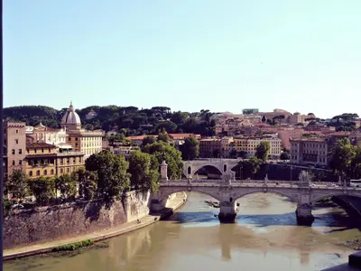 a bridge over a river with a city in the background at Trastevere Charme in Rome