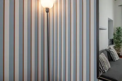 a room with a striped wall with a lamp at Ezio House in Rome