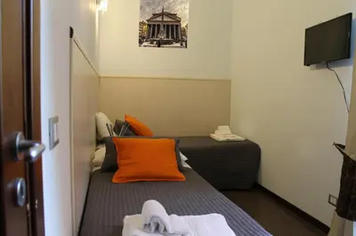 a small room with a bed with an orange pillow at Vatican Santamaura 39 in Rome