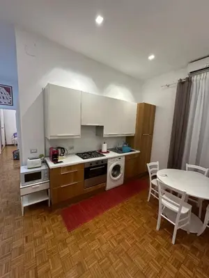 a kitchen with white cabinets and a table with chairs at Nova Domus Colosseo in Rome