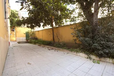 a sidewalk with a yellow wall and a tree at Sara Holiday House in Rome