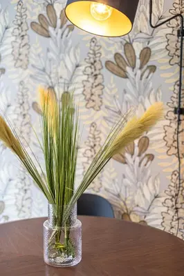 a glass vase with grass in it sitting on a table at Cornelia Elegance House in Rome