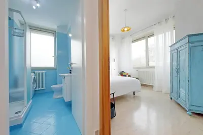 a blue and white bedroom with a bed and a bathroom at Homely Flat Porta Maggiore in Rome
