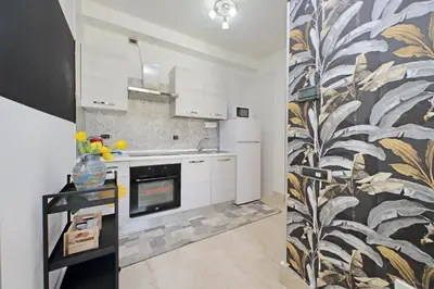 a kitchen with white cabinets and a black and white wallpaper at Homely Flat Porta Maggiore in Rome