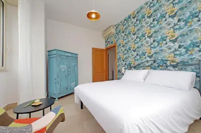 a bedroom with a white bed and a blue wall at Homely Flat Porta Maggiore in Rome