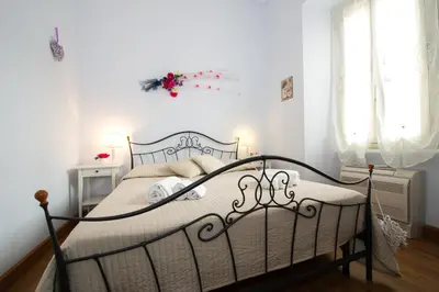 a bedroom with a bed with white walls and windows at Home Candia in Rome