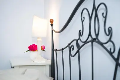 a bed with a lamp and a pink flower on a table at Home Candia in Rome