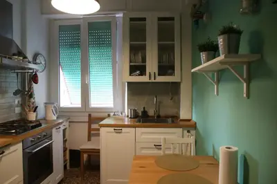 a kitchen with green walls and white cabinets and a table at Porta Maggiore Modern Apartment in Rome