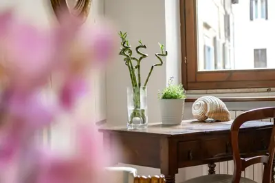 a table with a vase with flowers and a window at Pantheon Boutique Apartment in Rome